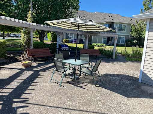 A patio with a table and chairs under an umbrella.