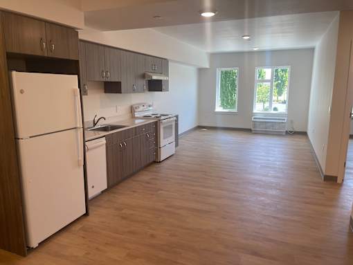 A kitchen with a white refrigerator and wooden floors.