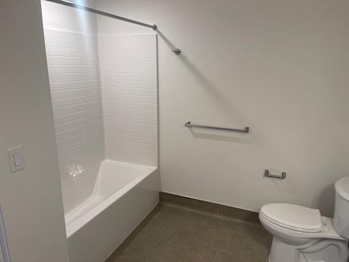 A white toilet sits next to a bathtub in a bathroom.