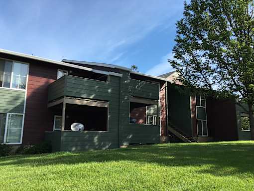 A green house with a red and brown one behind it.