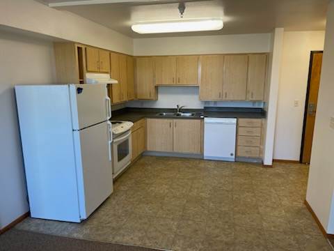 A kitchen with a white refrigerator and wooden cabinets.