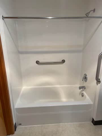 A white bathtub with a silver faucet and grab bar.
