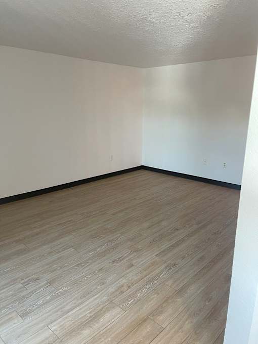 A room with wooden flooring and white walls.