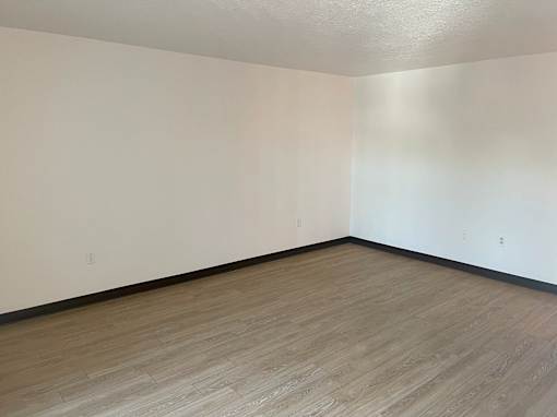 A room with wooden flooring and white walls.