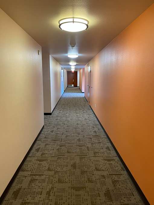 A long hallway with a carpeted floor and orange walls.