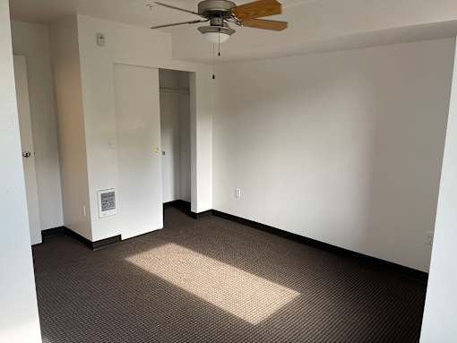 A room with a ceiling fan and carpeted floor.