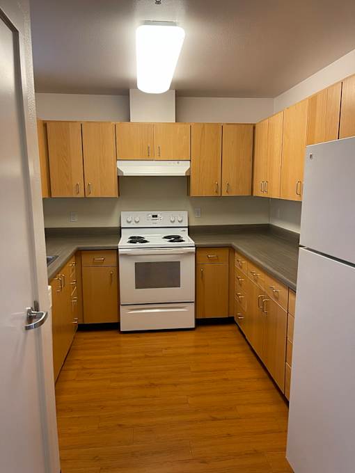 A kitchen with wooden cabinets and a white stove top oven.