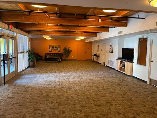 A spacious room with a carpeted floor and wooden beams on the ceiling.
