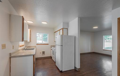 A kitchen with white appliances and wooden floors.