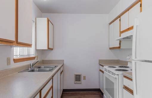 A kitchen with white appliances and wooden cabinets.