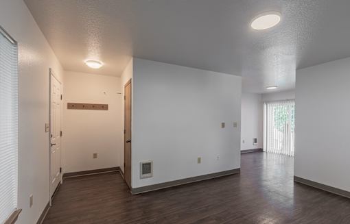 A spacious room with white walls and wooden flooring.