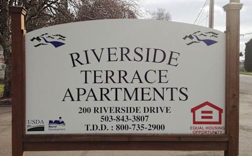 A sign for Riverside Terrace Apartments with contact information and logos.