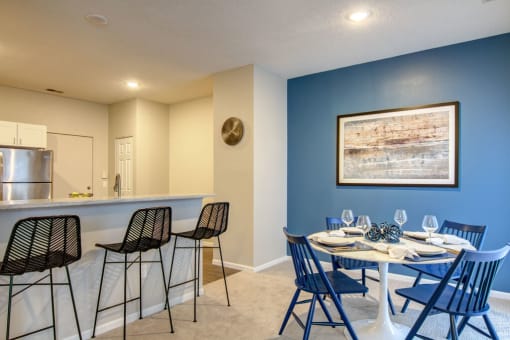 a dining area with a table and chairs and a kitchen in the background