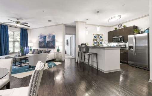 a living room and kitchen area with white walls and wood flooring