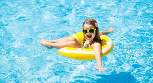 a girl in a swimming pool with a yellow float