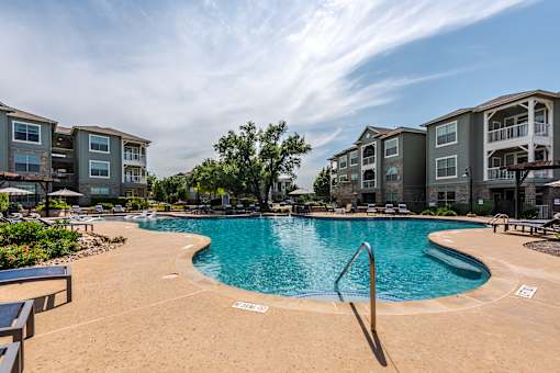 A pool with builings in the background. at 95twenty  Apartments, Austin, TX