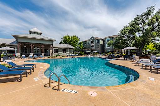 A large swimming pool with a building in the background at 95twenty Apartments, Austin