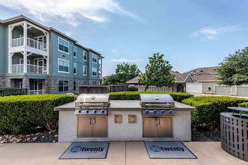 A bbq grill is in front of a building with a sign at 95twenty  Apartments, Austin, TX