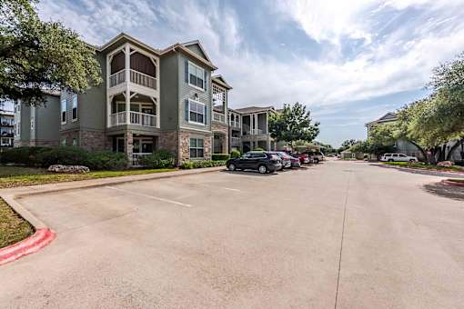 A parking lot in front of a multi-story apartment building at 95twenty Apartments, Austin