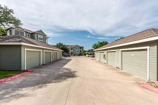 A row of garages with a driveway in between them at 95twenty Apartments, Austin, 78717