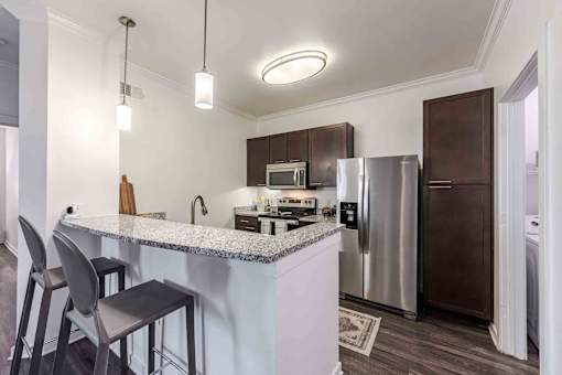 A kitchen with a bar area and a refrigerator at 95twenty Apartments, Austin, TX, 78717