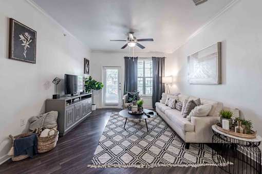 A living room with a couch, a coffee table, and a television at 95twenty  Apartments, Austin, TX