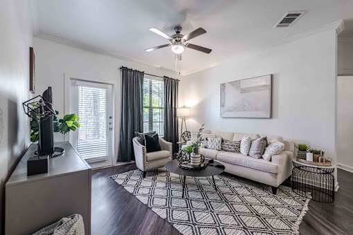 A living room with a white couch, a coffee table, and a ceiling fan at 95twenty  Apartments, Austin, TX