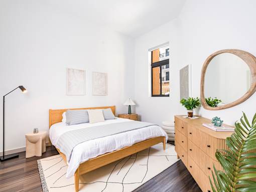A bedroom with a large bed and a wooden dresser.