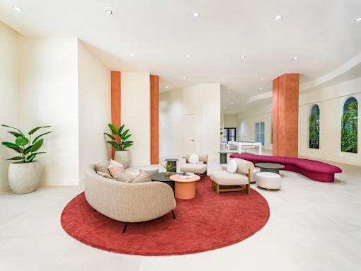 A living room with a red rug and a large chair.