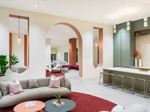 A modern living room with a grey sofa, a round table with a plant on it, and a red carpet.