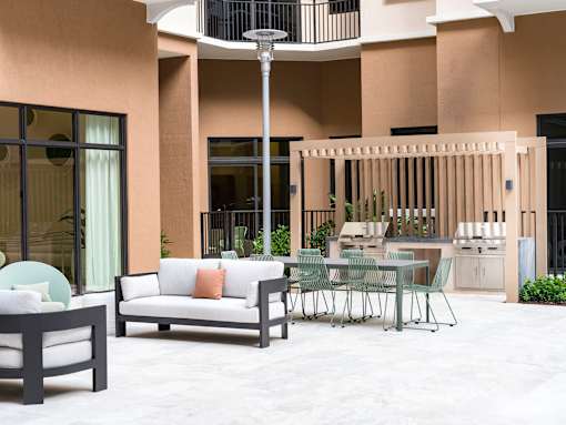 A patio with a white couch, a black table, and a glass table with chairs.
