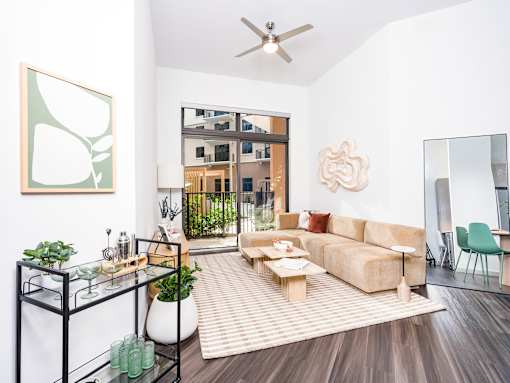 A living room with a couch, a chair, a table, a potted plant, and a mirror.