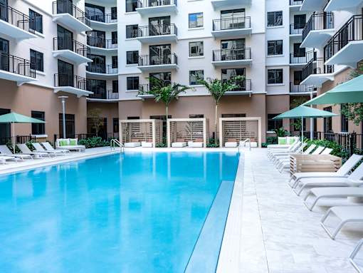 A large swimming pool in front of a multi-story apartment building.