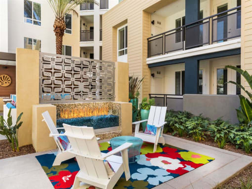 a patio with two chairs and a fire place in front of an apartment building