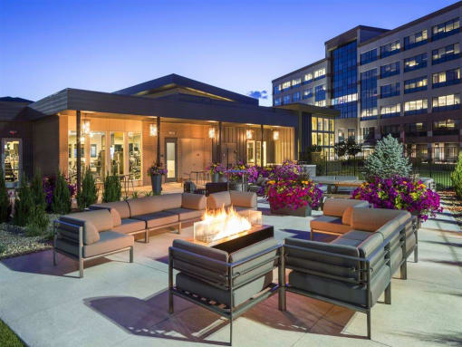 a patio with couches and a fire pit in front of a building