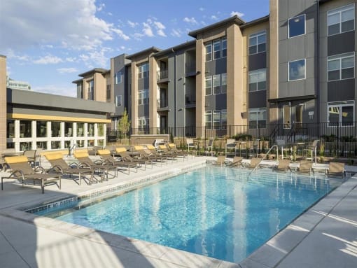 a swimming pool with chaise lounge chairs and a building in the background