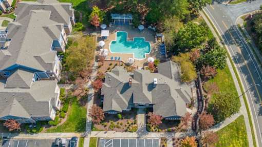 An aerial view of a residential area with houses, a swimming pool, and a parking lot.