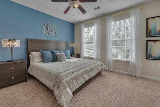 A bedroom with a bed, dresser, and ceiling fan.