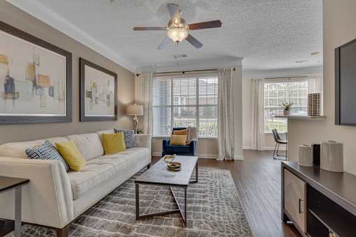 A living room with a white couch, a coffee table, and a ceiling fan.
