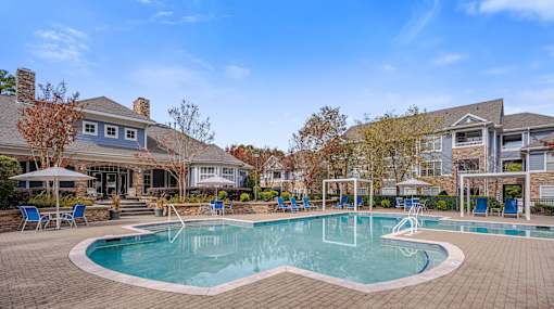 A large swimming pool surrounded by a brick patio and lounge chairs.