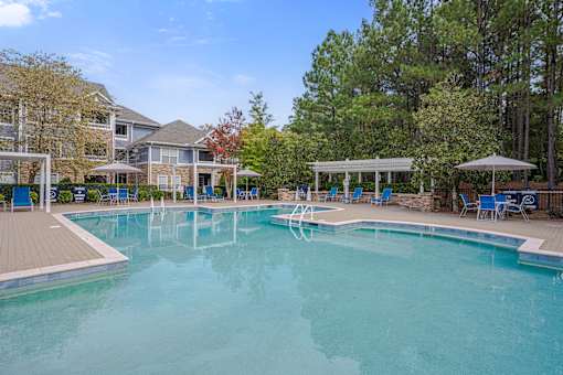 A large swimming pool surrounded by trees and a building.