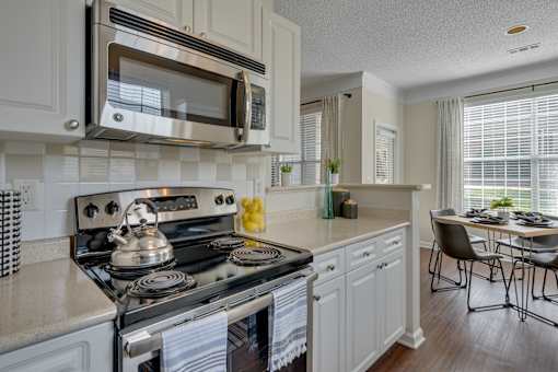 A modern kitchen with a stove, microwave, and a dining table.
