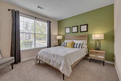 A bedroom with a bed, nightstand, and window.