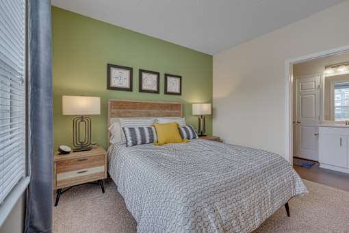 A bedroom with a bed, nightstands, and pictures on the wall.