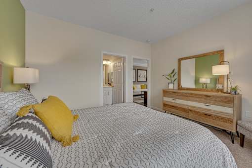 A bedroom with a bed, dresser, and mirror.