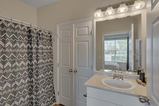 A bathroom with a sink, mirror, and shower curtain.
