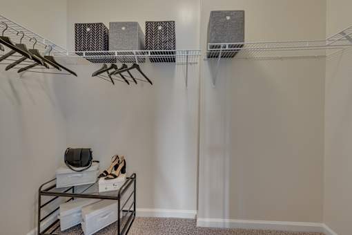 A room with a shelf, hangers, and shoes.
