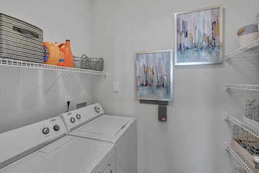 A laundry room with a washer and dryer and a painting on the wall.