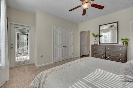 A bedroom with a white bedspread and a ceiling fan.