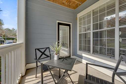 A small table with a potted plant on it is on a porch.